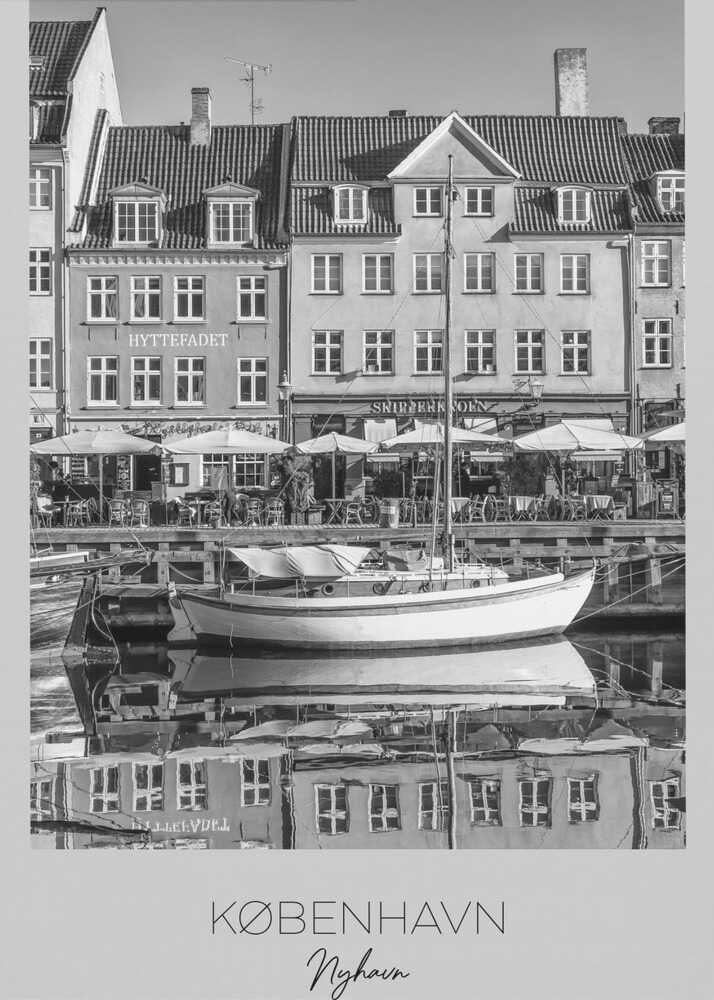 A black and white framed poster of Nyhavn in Copenhagen. The photograph features classic Danish buildings lining a canal, with a sailboat moored in the water. The buildings and boat are perfectly reflected in the still water. At the bottom, text reads 'KØBENHAVN', 'Nyhavn', and 'DANMARK'. Wall Art