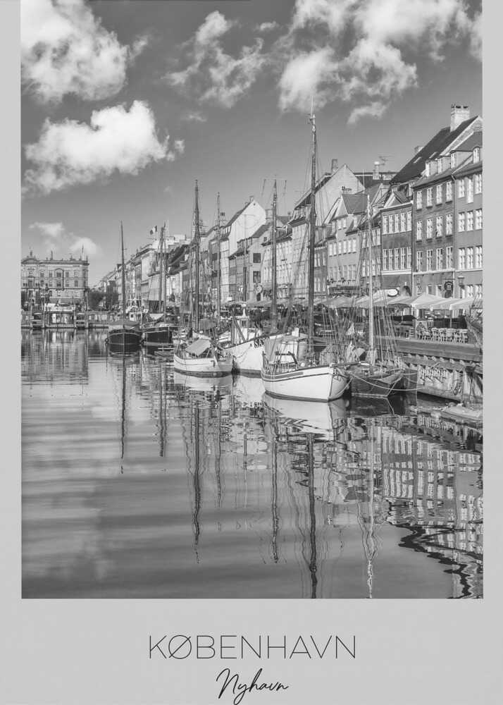 A black and white poster of Nyhavn harbor in Copenhagen. The photograph shows traditional sailboats and ships moored along a canal, with a line of historic, multi-story buildings on the far bank. The sky has fluffy clouds, and the entire scene is reflected in the calm water. The poster has a white border with the text 'KØBENHAVN', 'Nyhavn', and 'DANMARK' at the bottom, and is shown within a black frame. Poster