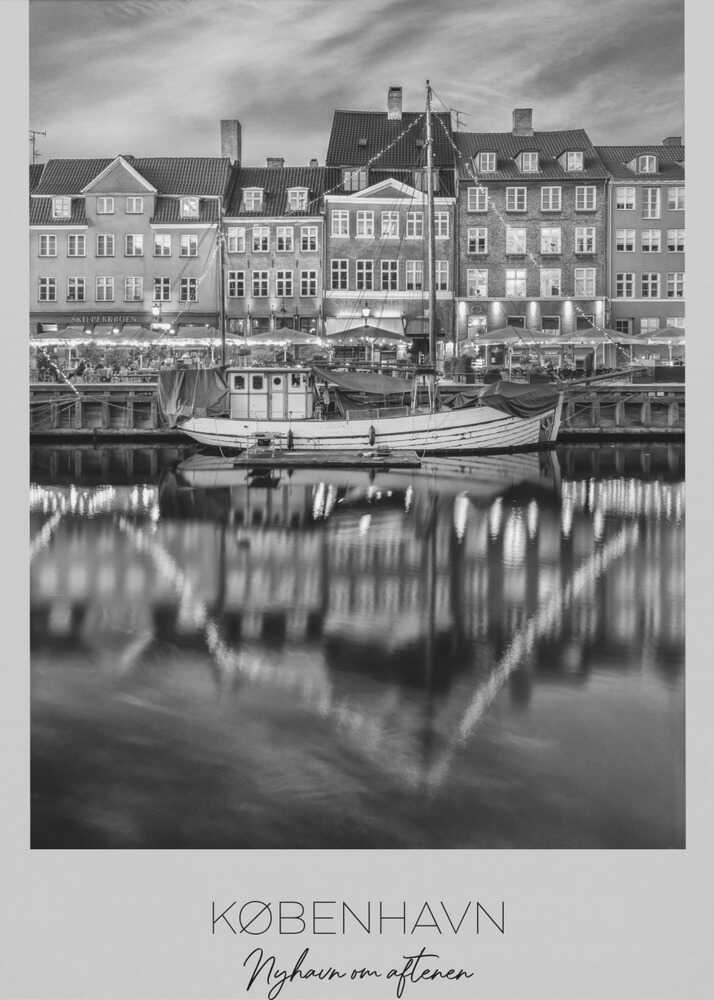 A black and white poster of Nyhavn harbor in Copenhagen at night. Historic buildings with glowing windows line the canal, and their lights create shimmering reflections in the water. A boat is docked in the foreground. The poster has text at the bottom that reads 'KØBENHAVN, Nyhavn om aftenen, DANMARK'. Poster