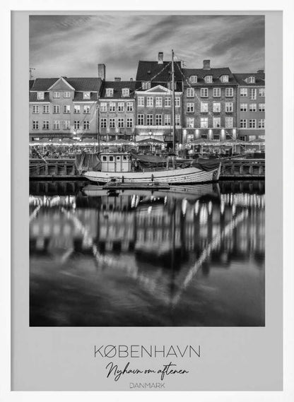 A black and white poster of Nyhavn harbor in Copenhagen at night. Historic buildings with glowing windows line the canal, and their lights create shimmering reflections in the water. A boat is docked in the foreground. The poster has text at the bottom that reads 'KØBENHAVN, Nyhavn om aftenen, DANMARK'. Poster