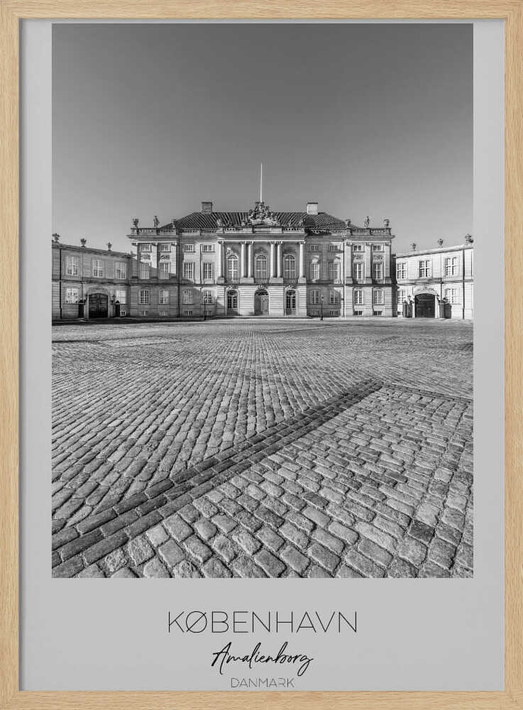 A framed, vertical black and white photograph of Amalienborg Palace in Copenhagen. The shot is taken from a low angle, emphasizing the large cobblestone square in the foreground. The palace stands symmetrically in the background under a clear sky. At the bottom of the poster, text reads 'KØBENHAVN', 'Amalienborg', and 'DANMARK'. Poster