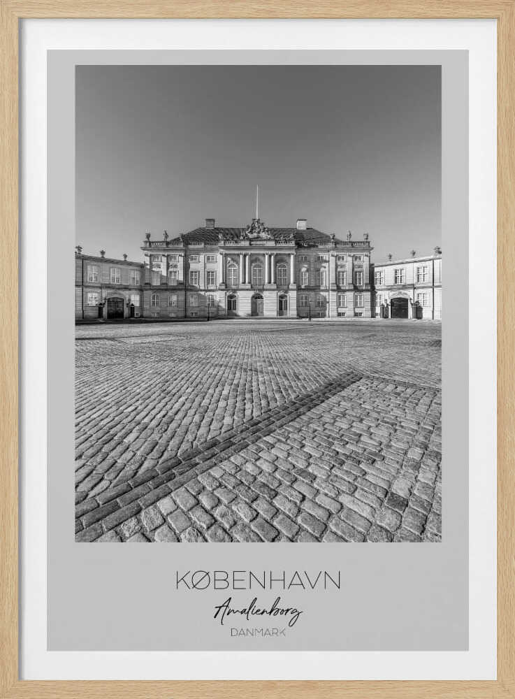 A framed, vertical black and white photograph of Amalienborg Palace in Copenhagen. The shot is taken from a low angle, emphasizing the large cobblestone square in the foreground. The palace stands symmetrically in the background under a clear sky. At the bottom of the poster, text reads 'KØBENHAVN', 'Amalienborg', and 'DANMARK'. Poster