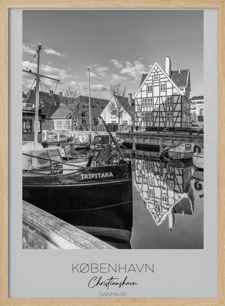 A black and white travel poster featuring a photo of Christianshavn in Copenhagen. The scene shows a boat named 'TRIPITAKA' docked in a canal, with a prominent half-timbered building across the water, its reflection visible on the surface. The bottom of the poster has text that reads 'KØBENHAVN', 'Christianshavn', and 'DANMARK'. Artwork