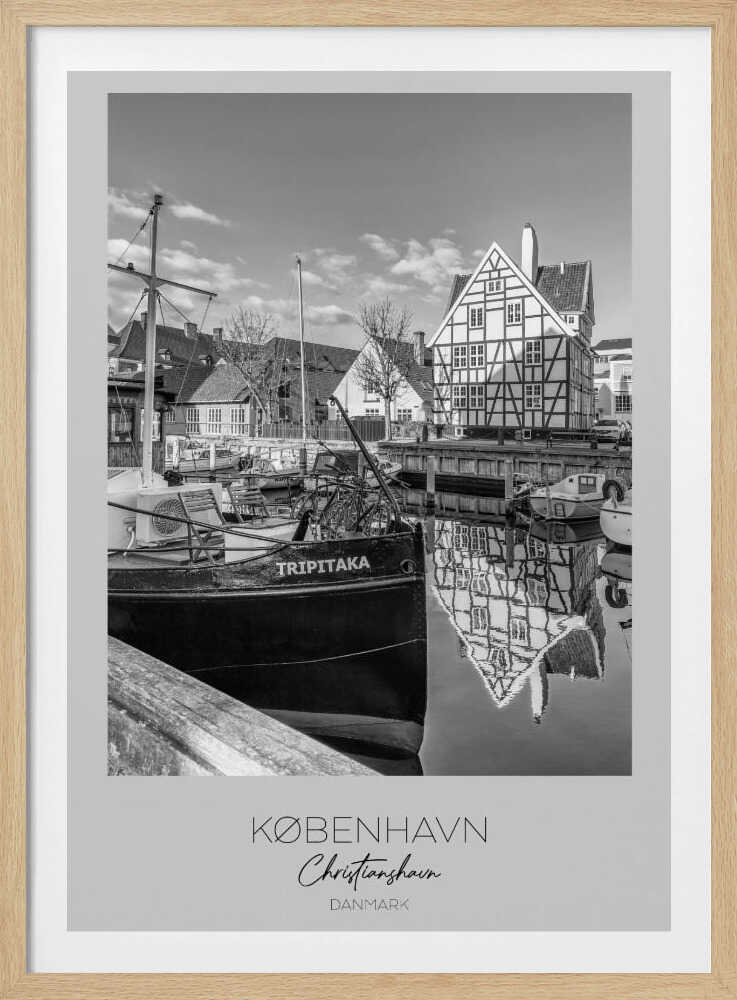 A black and white travel poster featuring a photo of Christianshavn in Copenhagen. The scene shows a boat named 'TRIPITAKA' docked in a canal, with a prominent half-timbered building across the water, its reflection visible on the surface. The bottom of the poster has text that reads 'KØBENHAVN', 'Christianshavn', and 'DANMARK'. Artwork