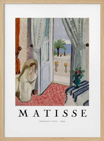 A framed art print of Henri Matisse's painting 'Intérieur à Nice - 1939'. The painting depicts a woman in a white robe sitting in a sunlit room with an open door leading to a balcony overlooking the sea and a palm tree. The poster has a white border with the artist's name and the title below the artwork. Artwork