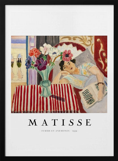 A poster featuring Henri Matisse's 1939 painting, 'Femme et Anemones'. The artwork depicts a woman in a colorful top reclining on a couch, holding a book. Beside her, on a red and white striped tablecloth, sits a vase filled with vibrant anemone flowers. The poster has a black frame and white matting, with 'MATISSE' printed below the image. Artwork