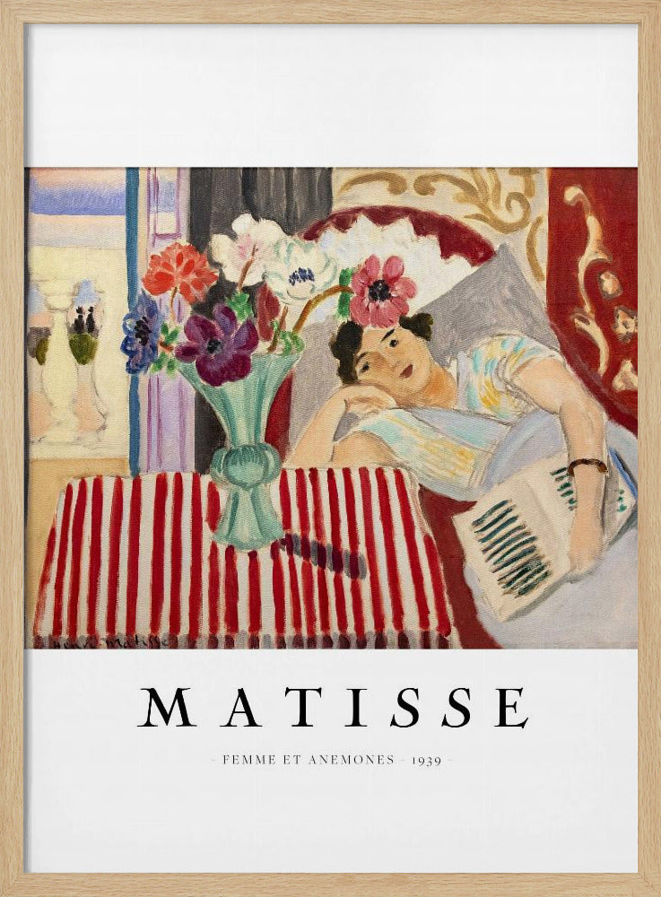 A poster featuring Henri Matisse's 1939 painting, 'Femme et Anemones'. The artwork depicts a woman in a colorful top reclining on a couch, holding a book. Beside her, on a red and white striped tablecloth, sits a vase filled with vibrant anemone flowers. The poster has a black frame and white matting, with 'MATISSE' printed below the image. Artwork