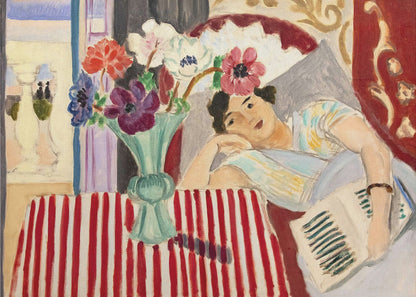 A Fauvist-style painting by Henri Matisse depicting a woman in a colorful blouse reclining with a book. Beside her is a table with a bold red-and-white striped cloth holding a light green vase with red, purple, and white anemone flowers. Print