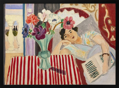 A Fauvist-style painting by Henri Matisse depicting a woman in a colorful blouse reclining with a book. Beside her is a table with a bold red-and-white striped cloth holding a light green vase with red, purple, and white anemone flowers. Print