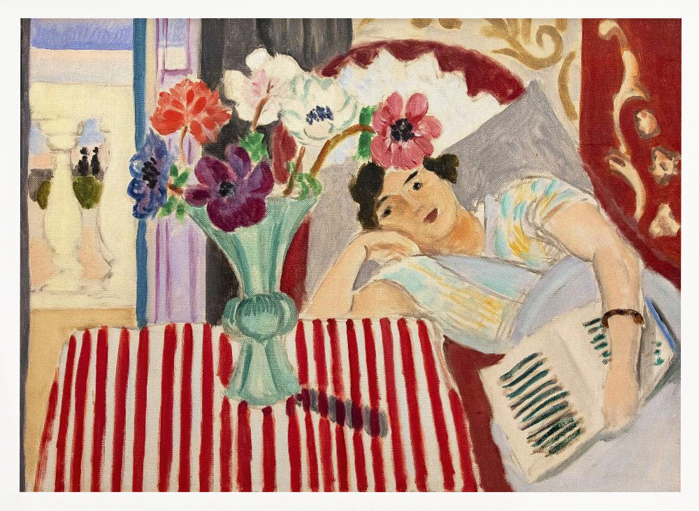 A Fauvist-style painting by Henri Matisse depicting a woman in a colorful blouse reclining with a book. Beside her is a table with a bold red-and-white striped cloth holding a light green vase with red, purple, and white anemone flowers. Print