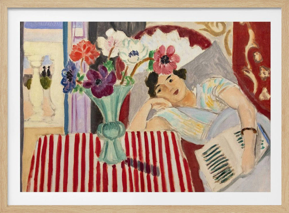 A Fauvist-style painting by Henri Matisse depicting a woman in a colorful blouse reclining with a book. Beside her is a table with a bold red-and-white striped cloth holding a light green vase with red, purple, and white anemone flowers. Print