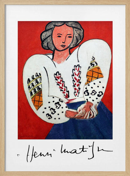 A framed art print of Henri Matisse's 'La Blouse Roumaine' (The Romanian Blouse). The painting depicts a woman with dark, styled hair against a vibrant solid red background. She is wearing a voluminous white blouse with puffy, intricately decorated sleeves and a dark blue skirt. Her hands are clasped in front of her. Below the image is the signature 'Henri Matisse'. Wall Art