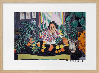 A framed print of the painting 'Woman with a Book' by Henri Matisse. The artwork features a woman in a red, white, and blue striped shirt sitting at a dark table filled with potted green plants and colorful fruit. She rests her head on her hand, looking out from the painting in a Fauvist style with bold colors and expressive brushwork. Poster