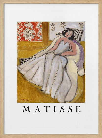 An art print poster of a Henri Matisse painting. The image features a woman with dark hair wearing a long, light-colored dress, reclining in a golden-yellow armchair. The background includes a red and white floral pattern and other decorative elements. The word 'MATISSE' is printed in large black letters below the artwork, all enclosed in a black frame. Decor
