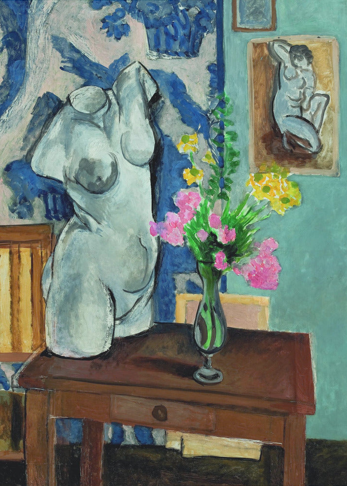 A colorful still life painting by Henri Matisse depicting a white plaster torso of a woman on a dark brown table next to a vase of bright pink and yellow flowers. The background features a blue and white patterned fabric and a light blue wall with a small framed nude drawing. Decor