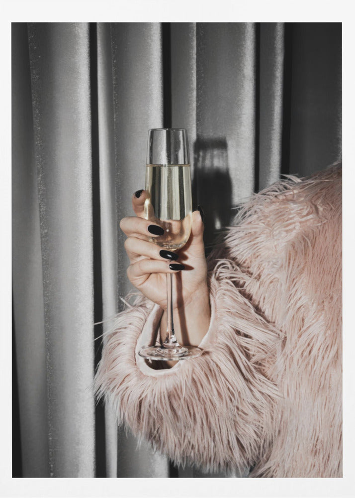 A close-up photograph of a woman's hand with black nail polish holding a tall, elegant flute of champagne. She is wearing a soft, shaggy pink faux fur coat, with a silver-gray curtain in the background, creating a luxurious and celebratory mood. Print