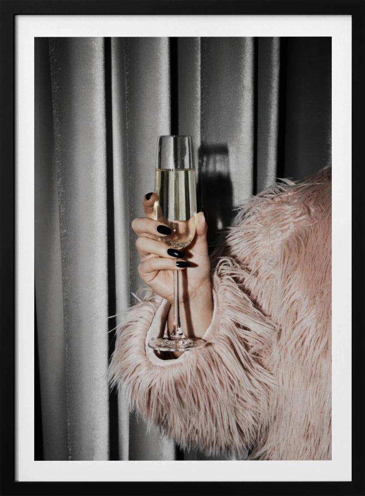 A close-up photograph of a woman's hand with black nail polish holding a tall, elegant flute of champagne. She is wearing a soft, shaggy pink faux fur coat, with a silver-gray curtain in the background, creating a luxurious and celebratory mood. Print