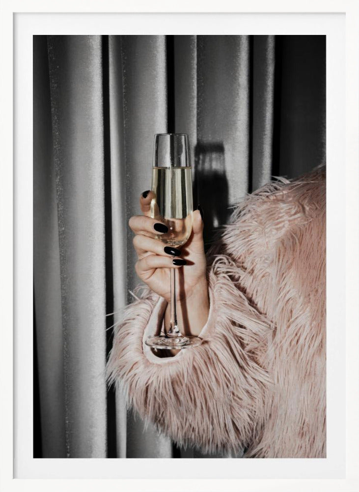 A close-up photograph of a woman's hand with black nail polish holding a tall, elegant flute of champagne. She is wearing a soft, shaggy pink faux fur coat, with a silver-gray curtain in the background, creating a luxurious and celebratory mood. Print
