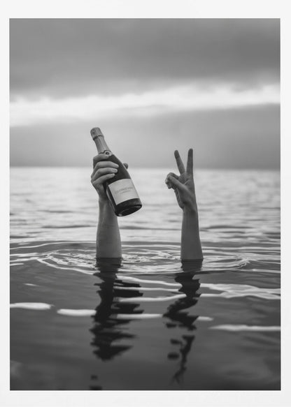 A black and white vertical photograph showing two arms sticking out of calm water. One hand holds a bottle of champagne, while the other makes a peace sign, all under a cloudy sky. Poster