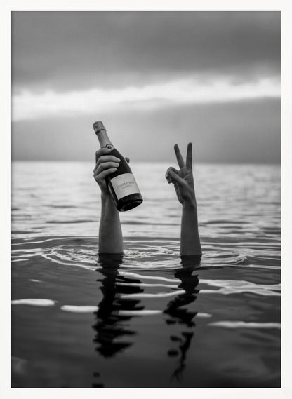 A black and white vertical photograph showing two arms sticking out of calm water. One hand holds a bottle of champagne, while the other makes a peace sign, all under a cloudy sky. Poster