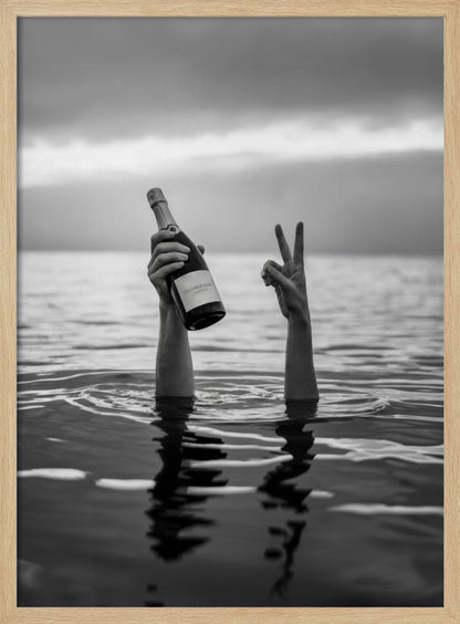 A black and white vertical photograph showing two arms sticking out of calm water. One hand holds a bottle of champagne, while the other makes a peace sign, all under a cloudy sky. Poster