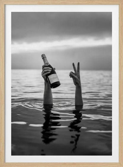 A black and white vertical photograph showing two arms sticking out of calm water. One hand holds a bottle of champagne, while the other makes a peace sign, all under a cloudy sky. Poster
