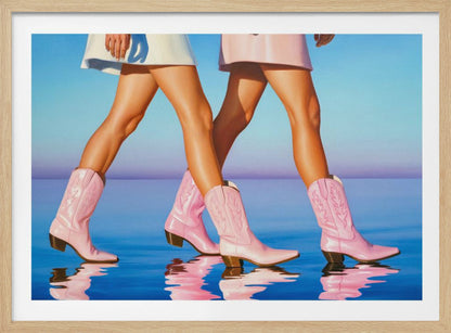 A pop art style painting of the legs of two women wearing matching pink cowboy boots and short skirts, walking across a reflective blue surface that mirrors their steps. The background is a gradient of blue and lavender, and the entire image is contained within a silver frame. Wall Art