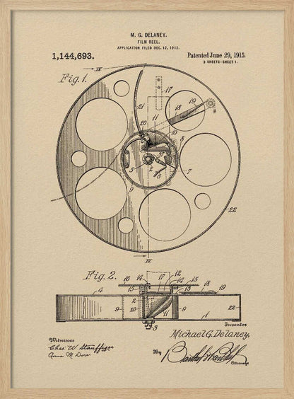 A framed vintage patent illustration of a film reel from 1915 by M.G. Delaney. The drawing is in black ink on a beige background, showing detailed schematics of the reel's mechanics from two different angles, complete with numbered parts, signatures, and patent information. Wall Art
