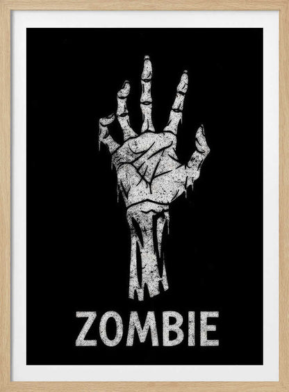 A black and white graphic of a distressed, skeletal zombie hand reaching up against a solid black background. Below the hand, the word 'ZOMBIE' is written in a bold, distressed font. The entire image is bordered by a thin black frame. Decor