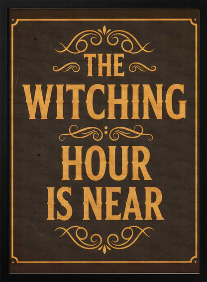 A framed vintage-style sign with a dark brown, distressed background. In a bold, golden-yellow serif font, the text reads 'THE WITCHING HOUR IS NEAR'. The text is adorned with ornate, swirling flourishes above, between, and below the lines. A thin golden-yellow border frames the entire design. Poster