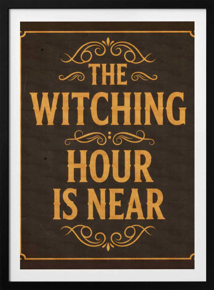 A framed vintage-style sign with a dark brown, distressed background. In a bold, golden-yellow serif font, the text reads 'THE WITCHING HOUR IS NEAR'. The text is adorned with ornate, swirling flourishes above, between, and below the lines. A thin golden-yellow border frames the entire design. Poster