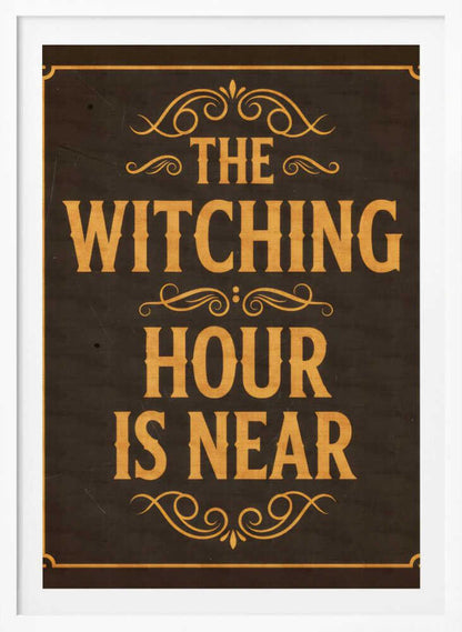 A framed vintage-style sign with a dark brown, distressed background. In a bold, golden-yellow serif font, the text reads 'THE WITCHING HOUR IS NEAR'. The text is adorned with ornate, swirling flourishes above, between, and below the lines. A thin golden-yellow border frames the entire design. Poster