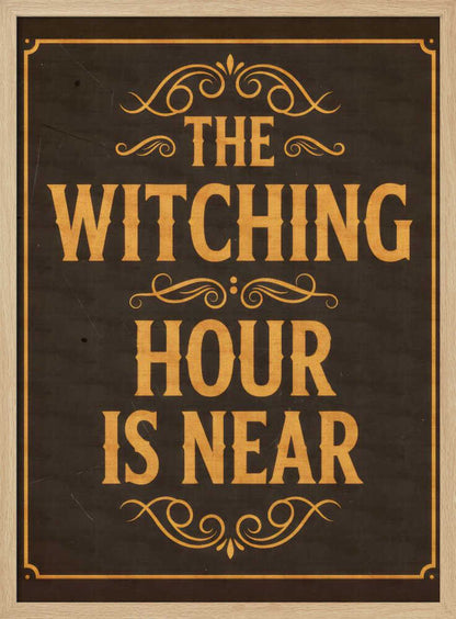 A framed vintage-style sign with a dark brown, distressed background. In a bold, golden-yellow serif font, the text reads 'THE WITCHING HOUR IS NEAR'. The text is adorned with ornate, swirling flourishes above, between, and below the lines. A thin golden-yellow border frames the entire design. Poster