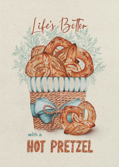 A vintage-style framed artwork featuring a watercolor illustration of a wicker basket overflowing with golden-brown pretzels. The text reads 'Life's Better with a HOT PRETZEL' in a warm brown font against a cream-colored textured background. A blue ribbon is tied around the basket, and light blue foliage is visible behind it. Poster