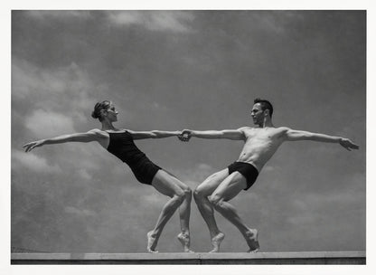 A black and white photograph of a male and female ballet dancer striking a symmetrical, athletic pose on a ledge. They hold hands, leaning away from each other in a display of strength and balance against a cloudy sky, all enclosed within a silver frame. Print