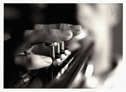 A dramatic, close-up, black and white photograph of a musician's fingers pressing down on the silver valves of a trumpet, with a soft, out-of-focus background. The image is enclosed in a brushed silver frame. Poster