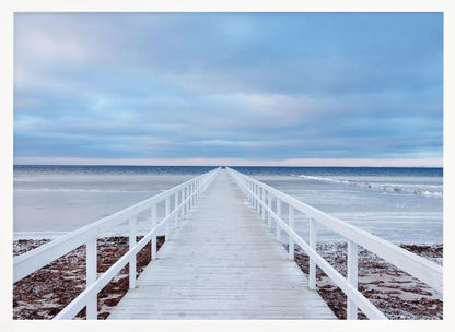 A framed photograph capturing a long, white wooden pier from a central perspective, leading the eye across a calm, icy sea towards the distant horizon under a cloudy blue sky. Print
