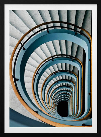 A high-angle, top-down photograph of a multi-story rectangular spiral staircase, creating a hypnotic, receding pattern. The steps are light gray marble, contrasted by shadows, and the balustrade is a striking light blue with a warm wooden handrail, leading down to a dark abyss at the center. Wall Art