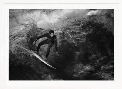 A dramatic black and white photograph of a surfer in a wetsuit skillfully riding down the face of a large, turbulent wave. The image is enclosed in a silver frame. Wall Art