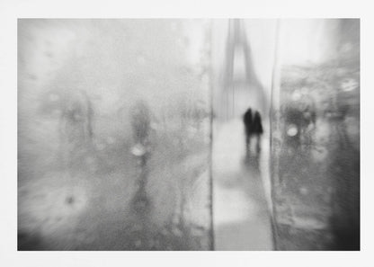 A framed, moody black and white photograph with a heavy blur effect, depicting a couple's silhouette walking towards the distant, hazy Eiffel Tower on what appears to be a rainy day in Paris. Artwork