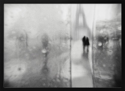 A framed, moody black and white photograph with a heavy blur effect, depicting a couple's silhouette walking towards the distant, hazy Eiffel Tower on what appears to be a rainy day in Paris. Artwork