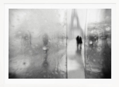 A framed, moody black and white photograph with a heavy blur effect, depicting a couple's silhouette walking towards the distant, hazy Eiffel Tower on what appears to be a rainy day in Paris. Artwork