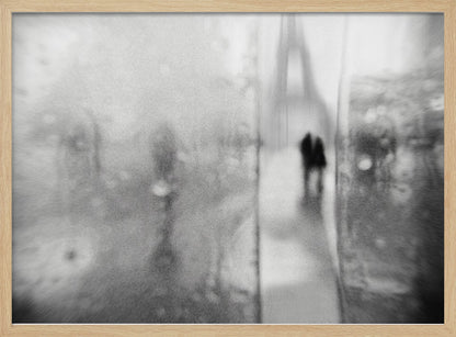A framed, moody black and white photograph with a heavy blur effect, depicting a couple's silhouette walking towards the distant, hazy Eiffel Tower on what appears to be a rainy day in Paris. Artwork