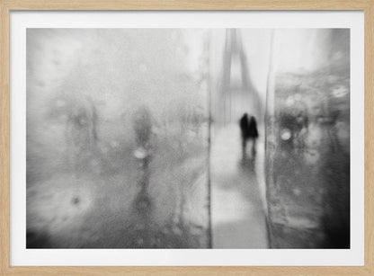 A framed, moody black and white photograph with a heavy blur effect, depicting a couple's silhouette walking towards the distant, hazy Eiffel Tower on what appears to be a rainy day in Paris. Artwork