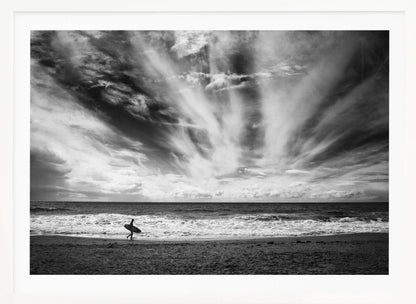 A dramatic black and white photograph of a lone surfer silhouetted against the sea, walking along a sandy beach. The sky is filled with spectacular, radiating clouds that stretch across the horizon, creating a powerful and moody atmosphere. The image is enclosed in a silver frame. Poster