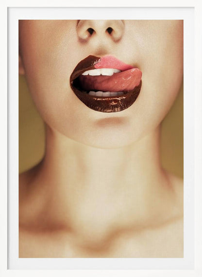 A close-up photograph of a woman's mouth with two-toned lipstick. The lips are mostly covered in glossy dark brown, with the upper right section in light pink. Her tongue is out, licking the pink part of her lip, revealing her white teeth. Print