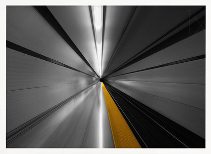 An abstract, long-exposure photograph from a first-person perspective inside a tunnel, creating a motion-blurred effect. The scene is mostly black and white, with lines radiating from a central vanishing point, but a single, bold yellow line runs down the center, adding a pop of selective color. The artwork is presented in a silver frame. Print