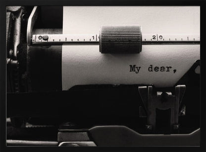 A close-up, black and white photograph of a vintage typewriter. A sheet of white paper is loaded, and the words 'My dear,' have just been typed, creating a sense of nostalgia and romance. The image is enclosed in a silver frame. Wall Art
