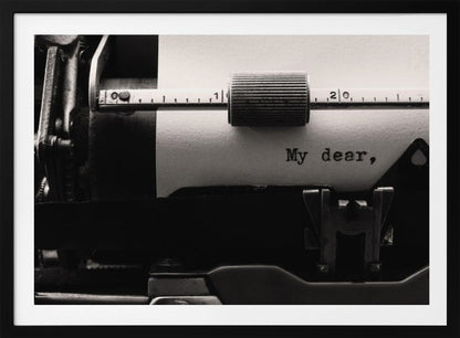 A close-up, black and white photograph of a vintage typewriter. A sheet of white paper is loaded, and the words 'My dear,' have just been typed, creating a sense of nostalgia and romance. The image is enclosed in a silver frame. Wall Art