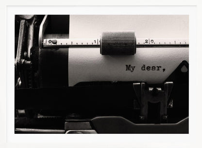 A close-up, black and white photograph of a vintage typewriter. A sheet of white paper is loaded, and the words 'My dear,' have just been typed, creating a sense of nostalgia and romance. The image is enclosed in a silver frame. Wall Art